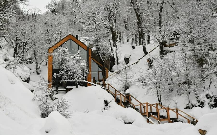 Refúgio de madeira entre árvores nevadas na floresta patagônica