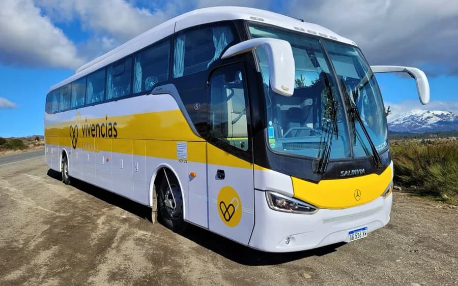 Ônibus próprio da Vivencias Travel estacionado com a cordilheira ao fundo