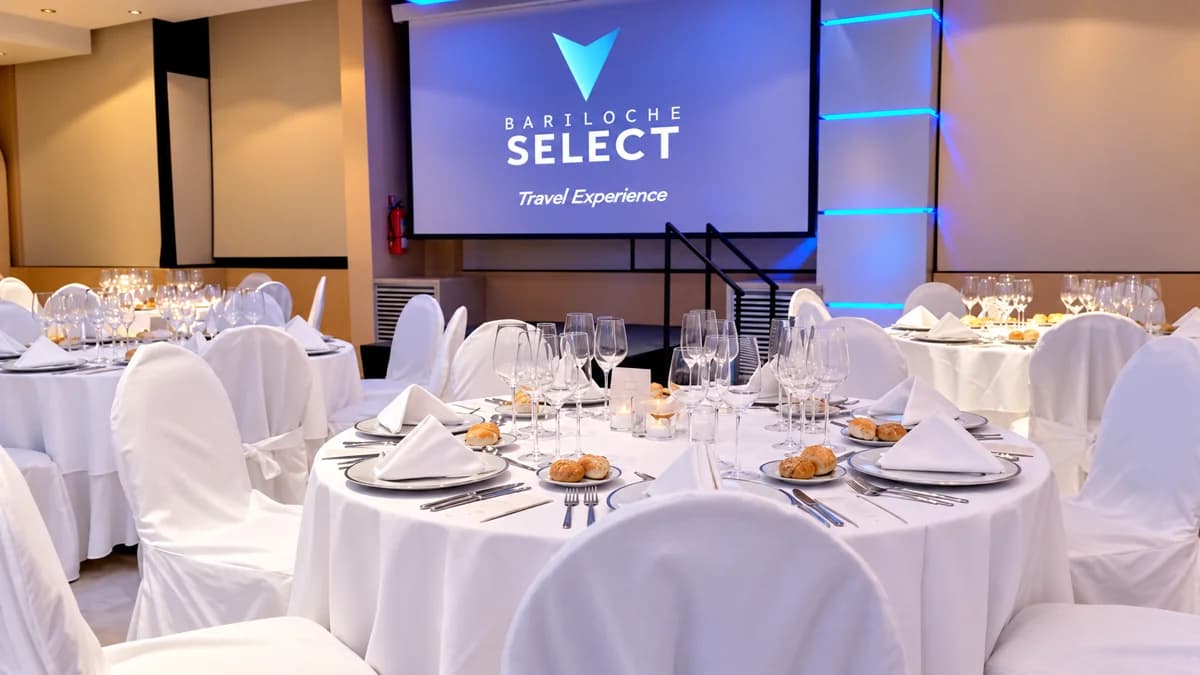 A room set up for a company event, with round tables dressed in white and a screen at the back