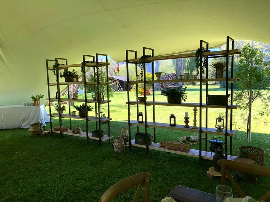 Estantería de hierro con plantas y objetos, montada como escenografía en el parque