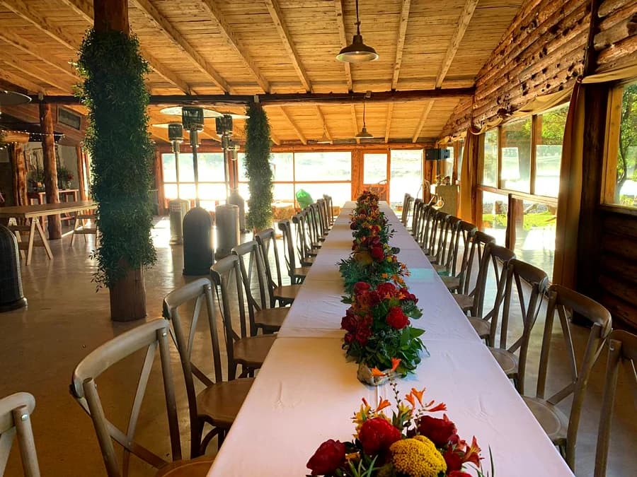 Quincho de madera con una mesa larga montada y centros de flores