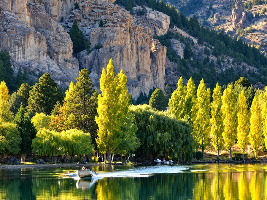 Lago con álamos amarillos y una embarcación pequeña cruzando